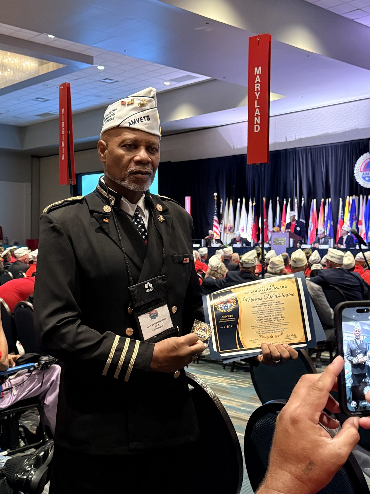 Second Vice Commander Marcus DeValentino holding his AMVETS Recognition Award certificate on the convention floor.