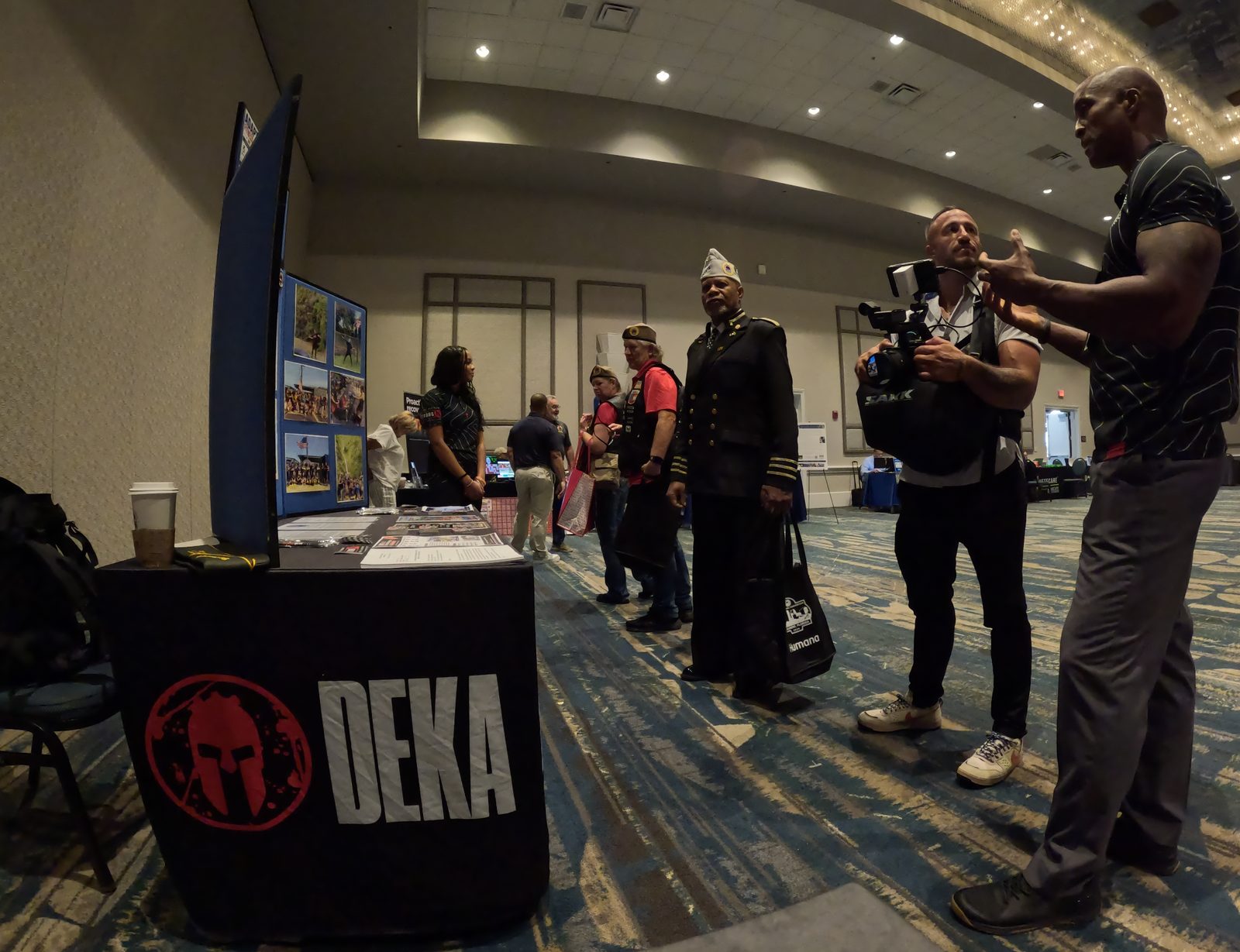 The AMVETS convention expo floor with program exhibits and attendees talking.